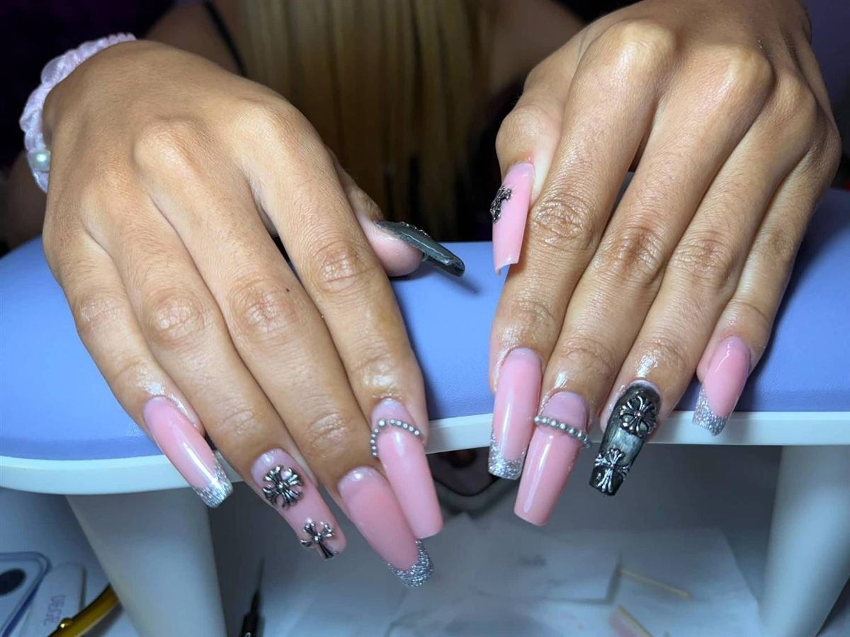 Long pink coffin nails with silver glitter tips and chrome cross charms